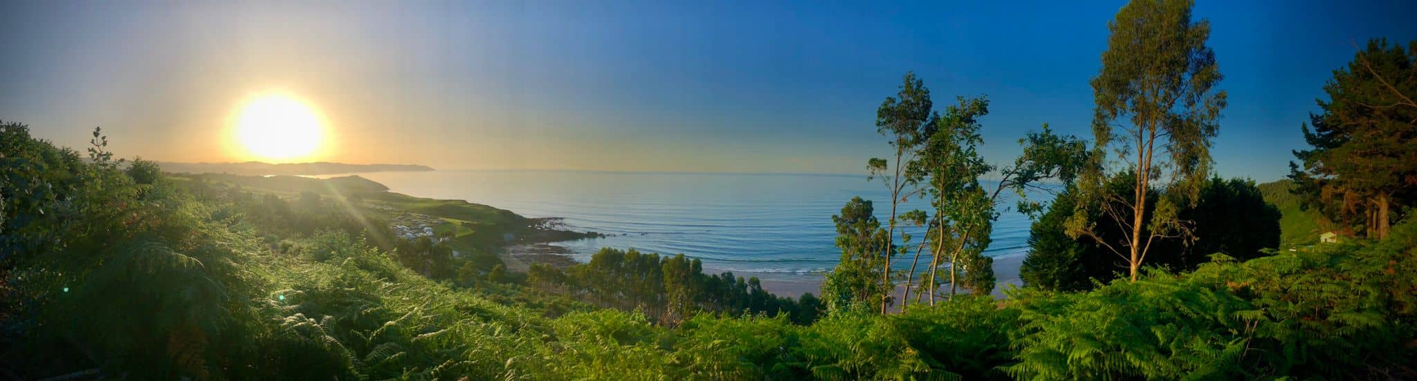 Amanecer panorámico sobre el mar Cantábrico y la playa Arenal de Morís desde el jardín de la casa